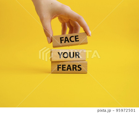 Face your Fears symbol. Wooden blocks with words Face your Fears. Beautiful yellow background. Businessman hand. Business and Face your Fears. Copy space. 95972501