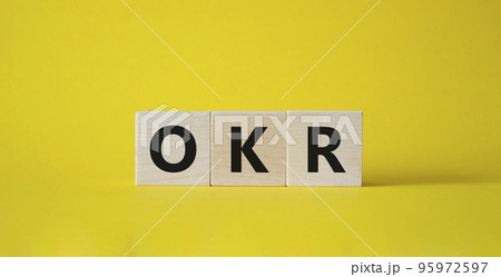 OKR objectives and key results symbol. Wooden cubes with words OKR objectives and key results. Beautiful yellow background. Business and OKR objectives and key results concept. Copy space. 95972597