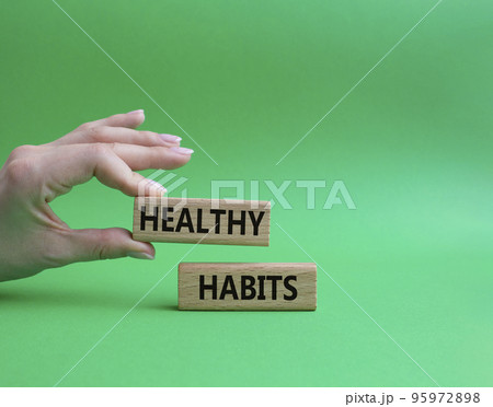 Healthy habits symbol. Concept word Healthy habits on wooden blocks. Beautiful green background. Businessman hand. Business and Healthy habits concept. Copy space 95972898