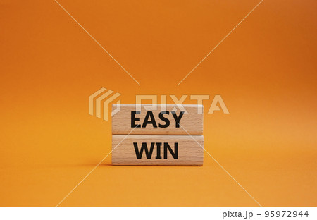 Easy win symbol. Wooden blocks with words 'Easy win'. Beautiful orange background. Business and 'Easy win' concept. Copy space. Easy win symbol. Wooden blocks with words 'Easy win'. Beautiful orange background. Business and 'Easy win' concept. Copy space. 95972944