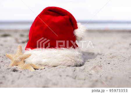 Santa Claus hat and starfish on the sandy beach 95973353