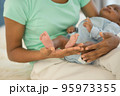 mother's hand holding little feet newborn baby's in her palm. 95973355
