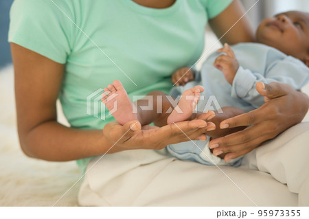 mother's hand holding little feet newborn baby's in her palm. 95973355
