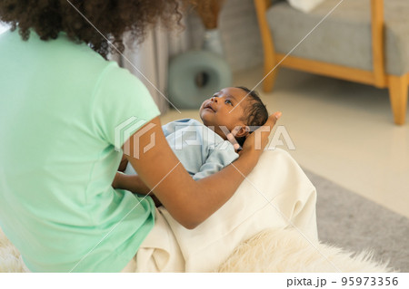 Mother African American holding one-month-old newborn baby gently. 95973356