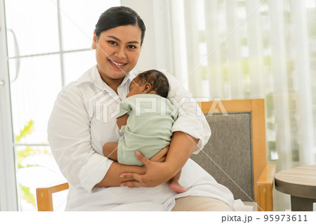Newborn baby one-month-old sleeping on the warm mother's chest. 95973611