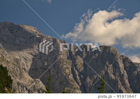 Paraglider flies in front of a massive rock wall Paraglider flies in front of a massive rock wall 95973647