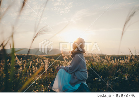 夕暮れの自然の中に佇む女性の写真 95973746