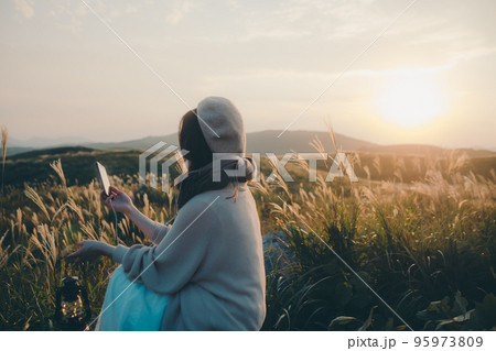 夕暮れの自然の中にスマホで音楽を聴きながら佇む女性の写真 夕暮れの自然の中にスマホで音楽を聴きながら佇む女性の写真 95973809