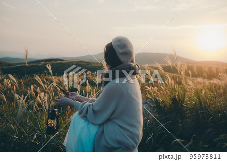 夕暮れの自然の中にスマホで音楽を聴きながら佇む女性の写真 夕暮れの自然の中にスマホで音楽を聴きながら佇む女性の写真 95973811