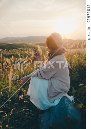 夕暮れの自然の中にスマホで音楽を聴きながら佇む女性の写真 夕暮れの自然の中にスマホで音楽を聴きながら佇む女性の写真 95973813