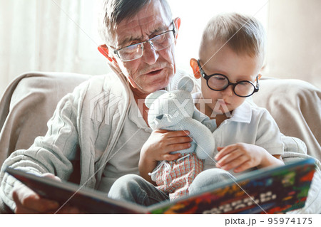 Grandfather and grandson are reading a book Grandfather and grandson are reading a book 95974175