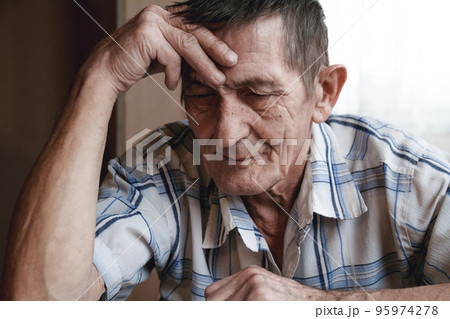 Senior sitting at the table and thinking about something or forg Senior sitting at the table and thinking about something or forg 95974278