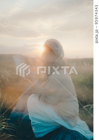 夕暮れの自然の中で読書をする女性の写真 95974343