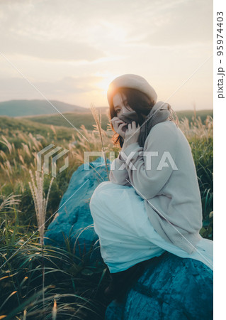夕暮れの自然の中で佇む女性の写真 95974403