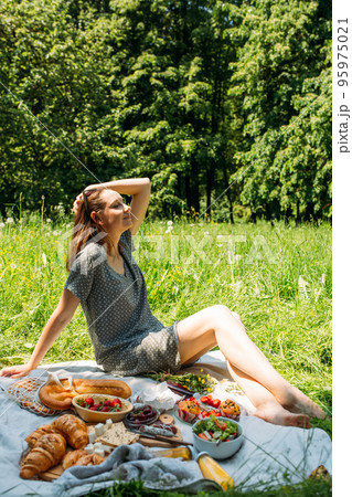 Beautiful woman on picnic. She smiles, eats strawberries and enjoys summer. Beautiful woman on picnic. She smiles, eats strawberries and enjoys summer. 95975021