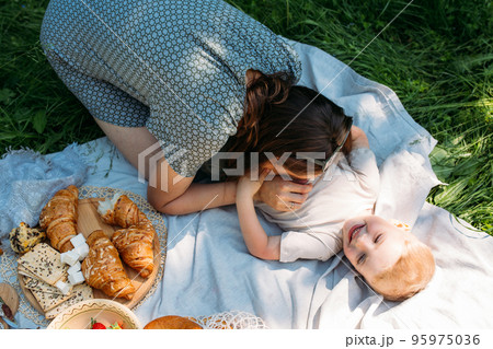 Family mom and son on picnic. Smiling and enjoying summer on blanket in park. Family mom and son on picnic. Smiling and enjoying summer on blanket in park. 95975036