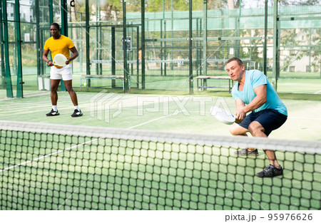 European man padel tennis player trains on the court European man padel tennis player trains on the court 95976626