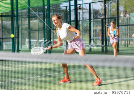European woman padel tennis player trains on the outdoor court European woman padel tennis player trains on the outdoor court 95976712
