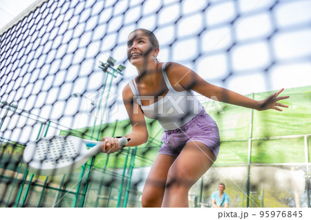 Young woman padel tennis player trains on the outdoor court 95976845