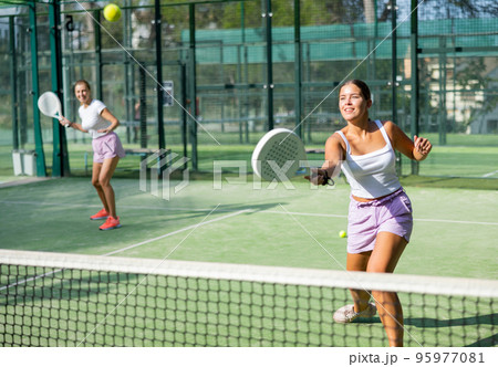 Active womans with enthusiasm playing padel on tennis court 95977081