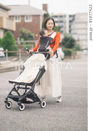 赤ちゃんを抱っこしてベビーカーを押すママ 赤ちゃんを抱っこしてベビーカーを押すママ 95977422