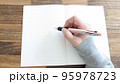 ノートに書こうとしている手 95978723