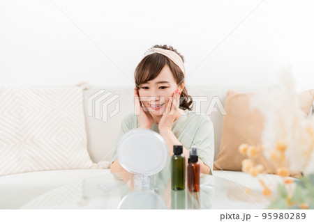 鏡を見ながら化粧品・コスメで保湿する日本人女性 95980289