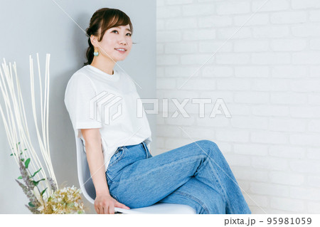 部屋で椅子に足を組むデニム姿の日本人女性 95981059