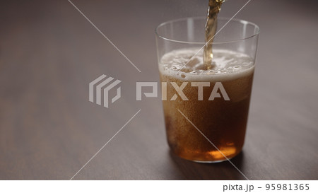 pour cola over ice cubes into tumbler glass on walnut table with copy space pour cola over ice cubes into tumbler glass on walnut table with copy space 95981365