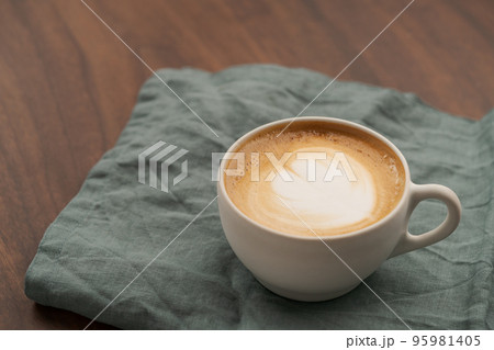 Flat white in white cup with simple latte art on walnut wood table with turquoise napkin 95981405