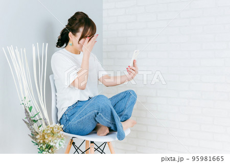 スマホで通話しながらショックを受けるアジア人女性（泣く・悲しい） 95981665