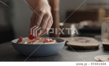 add cherry tomatoes to fusilli pasta in blue bowl 95981666