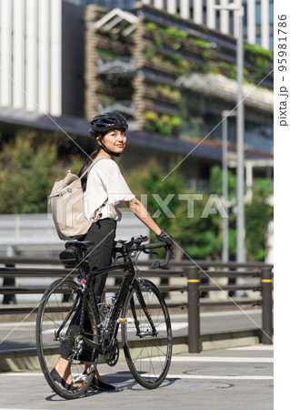 バックパックを背負って、ロードバイクを引いて歩くビジネスウーマン 振り返り バックパックを背負って、ロードバイクを引いて歩くビジネスウーマン 振り返り 95981786