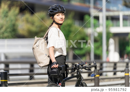 バックパックを背負って、ロードバイクを引いて歩くビジネスウーマン 振り返り バックパックを背負って、ロードバイクを引いて歩くビジネスウーマン 振り返り 95981792