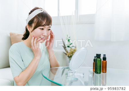 鏡を見ながら化粧品・コスメで保湿する日本人女性 95983782