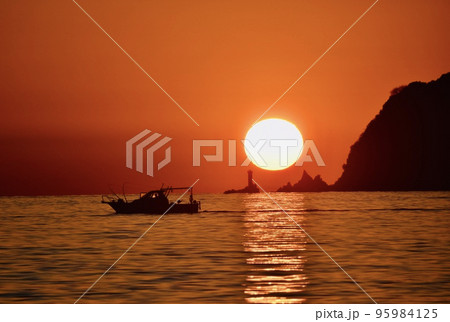 大水瀬島の灯台に沈む夕日と釣船 95984125