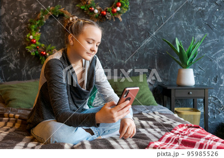 Smiling attractive young girl looking at mobile phone screen while holding Smiling attractive young girl looking at mobile phone screen while holding 95985526