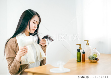 ドライヤーを使って髪を乾かす日本人女性（悩む・ダメージヘア） 95985841