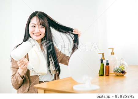 ドライヤーを使って髪を乾かす日本人女性（笑顔） 95985845