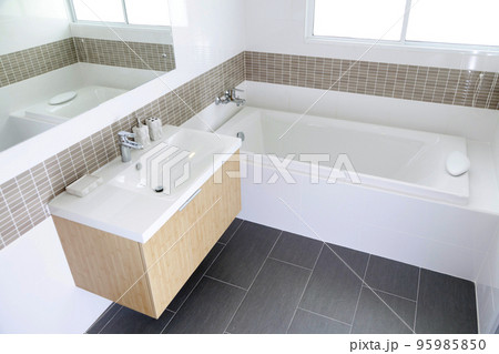 Sinks with mirrors and clean bathtub in modern bathroom with white tiled walls Sinks with mirrors and clean bathtub in modern bathroom with white tiled walls 95985850