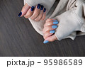 Gel nail design.Beautiful manicure. Nail polish is applied to the hand, polish is a blue color. Blue background closeup. Multi-colored blue manicure. 95986589