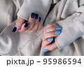 Gel nail design.Beautiful manicure. Nail polish is applied to the hand, polish is a blue color. Blue background closeup. Multi-colored blue manicure. 95986594