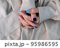 Gel nail design.Beautiful manicure. Nail polish is applied to the hand, polish is a blue color. Blue background closeup. Multi-colored blue manicure. 95986595
