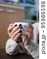 Gel nail design.Beautiful manicure. Nail polish is applied to the hand, polish is a blue color. Blue background closeup. Multi-colored blue manicure. 95986598