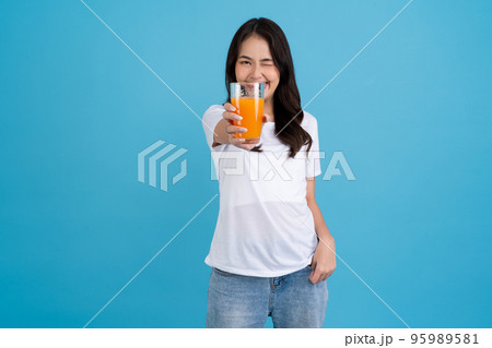Beautiful woman drinking orange from a glass Beautiful woman drinking orange from a glass 95989581