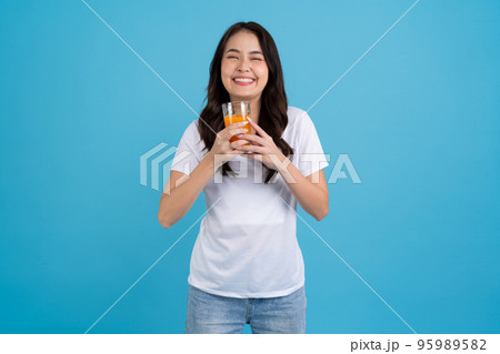 Beautiful woman drinking orange from a glass Beautiful woman drinking orange from a glass 95989582