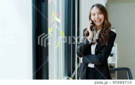 Happy young asian business woman wearing suit holding mobile phone 95989714