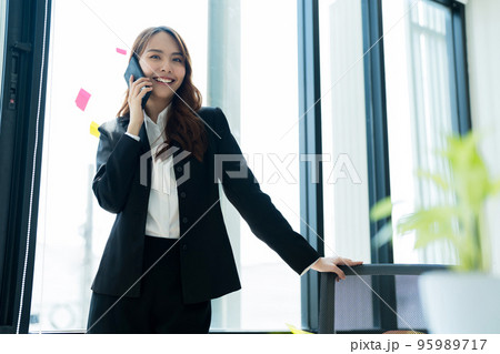 Happy young asian business woman wearing suit holding mobile phone 95989717