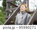 A red hair woman in the grey jacket sits in the city park 95990271