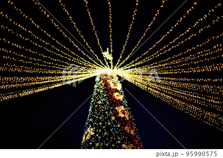 Long exposure night shot of a uniquely decorated main Christmas tree in the square after rain with reflection. Long exposure night shot of a uniquely decorated main Christmas tree in the square after rain with reflection. 95990575